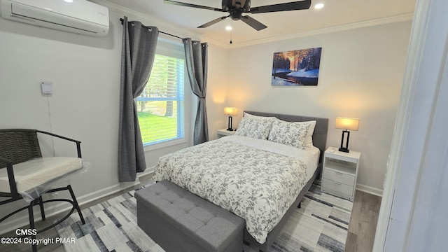 bedroom with wood finished floors, crown molding, baseboards, and a wall mounted AC