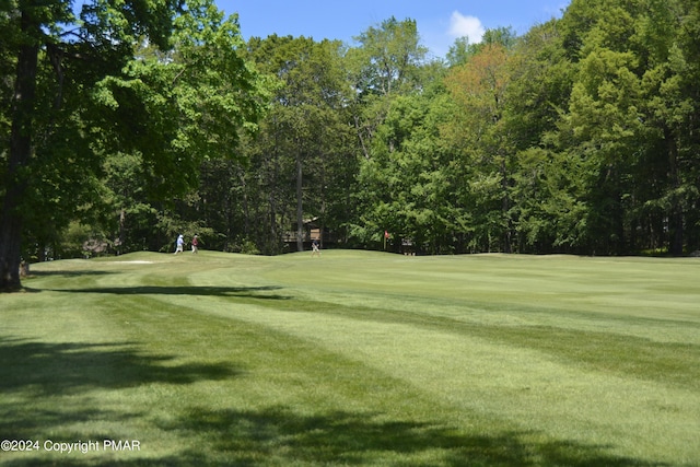 view of home's community featuring view of golf course and a lawn