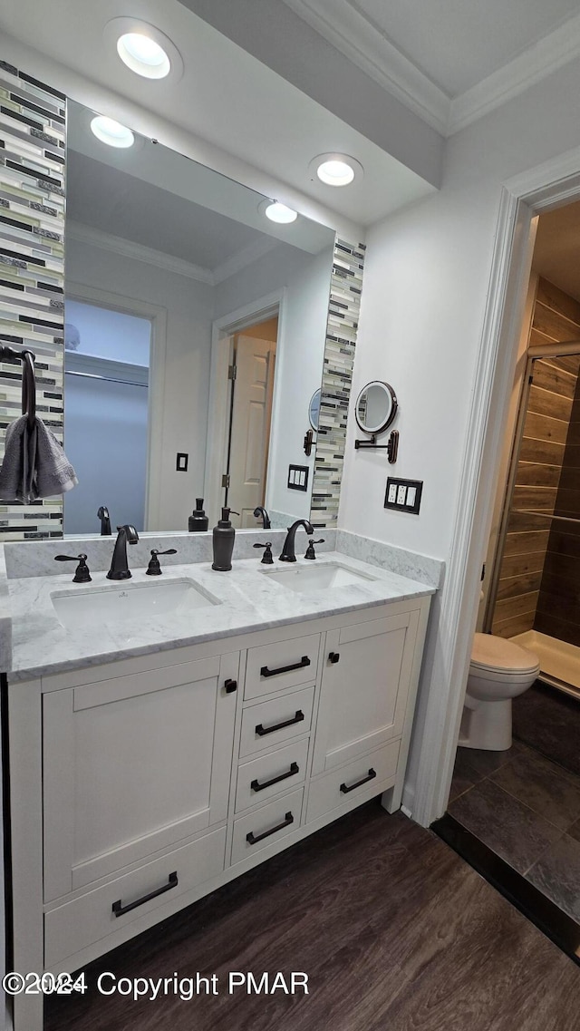 bathroom with wood finished floors, ornamental molding, and a sink