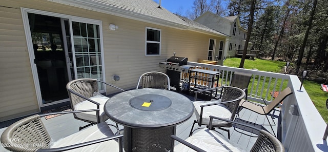 deck with grilling area, outdoor dining area, and a yard