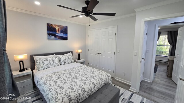 bedroom with baseboards, a ceiling fan, wood finished floors, crown molding, and a closet