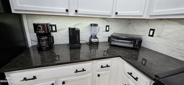 kitchen with dark stone counters, backsplash, and white cabinetry