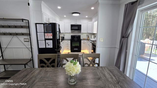 kitchen featuring tasteful backsplash, dark countertops, white cabinetry, and black appliances