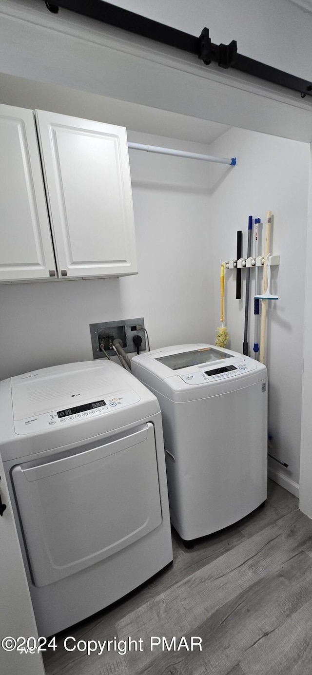 washroom featuring light wood-type flooring, washer and dryer, and cabinet space