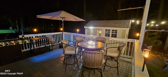 deck at twilight featuring outdoor dining space and an outdoor structure