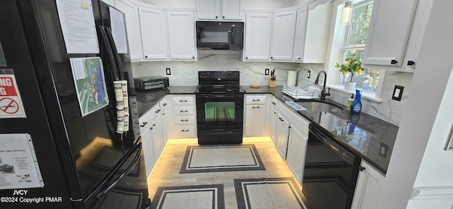 kitchen with dark stone countertops, a sink, black appliances, white cabinetry, and backsplash