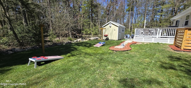 view of yard with a storage shed, a deck, and an outbuilding