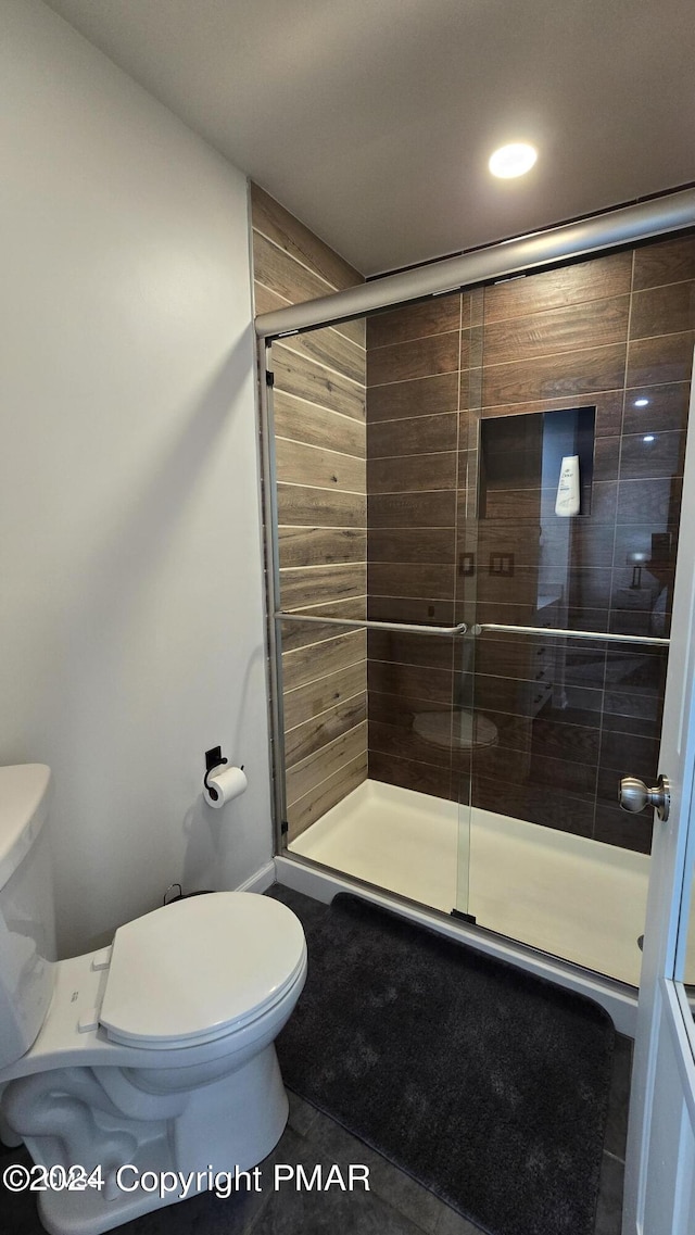 full bathroom with a stall shower, toilet, and tile patterned floors