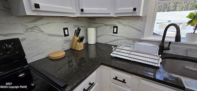 kitchen with dark stone counters, tasteful backsplash, white cabinets, and black electric range oven