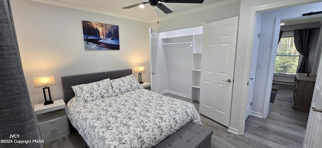 bedroom featuring a closet, ornamental molding, a ceiling fan, wood finished floors, and baseboards