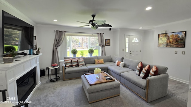 living area with a glass covered fireplace, crown molding, baseboards, and recessed lighting