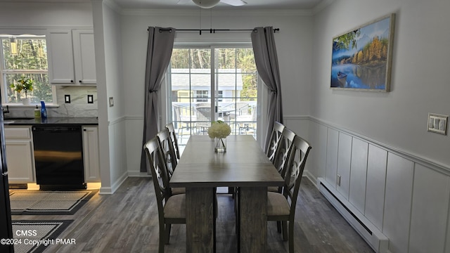 dining room with a baseboard heating unit, dark wood finished floors, crown molding, and wainscoting