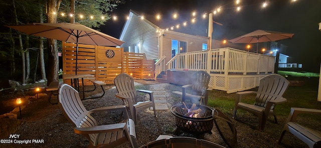 patio at twilight featuring a fire pit and a deck