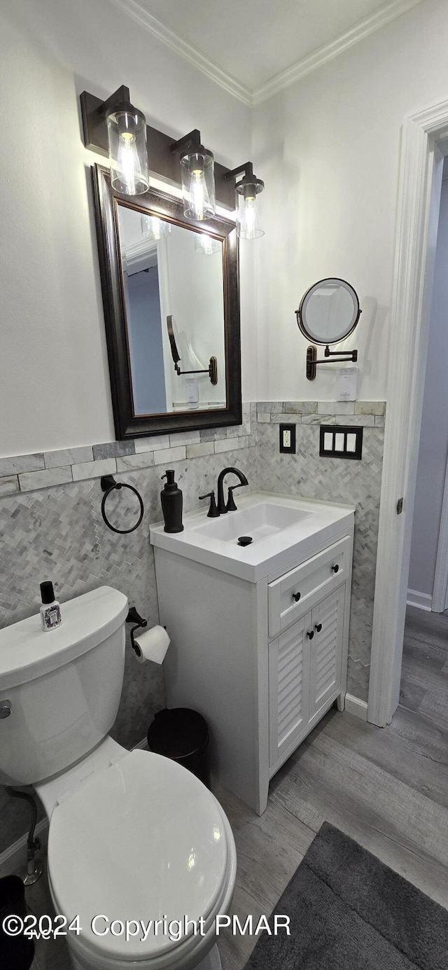 bathroom with crown molding, toilet, wainscoting, vanity, and wood finished floors