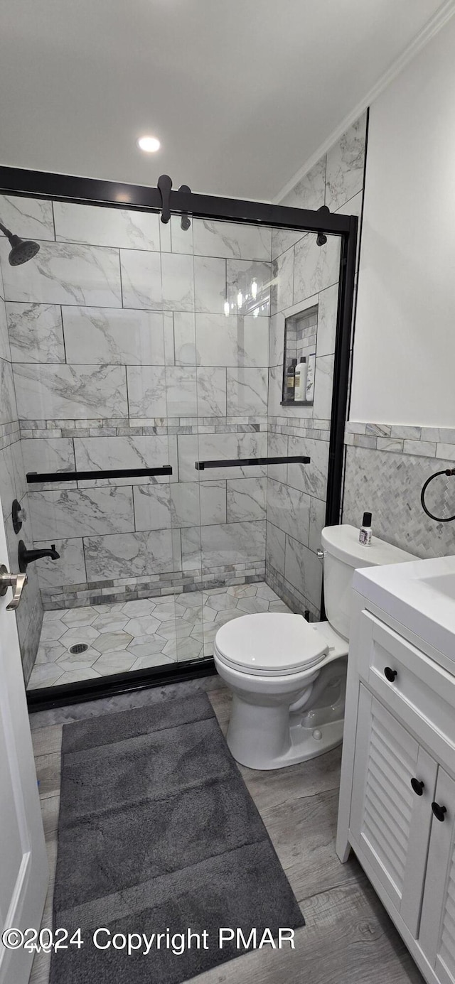 bathroom with toilet, vanity, tile walls, a stall shower, and crown molding