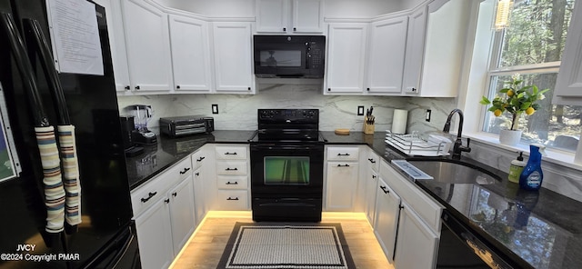 kitchen featuring tasteful backsplash, white cabinets, light wood-style flooring, black appliances, and a sink