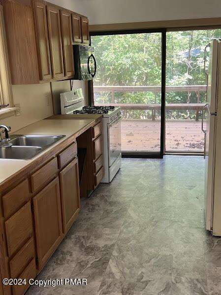 kitchen with light countertops, white appliances, and a sink