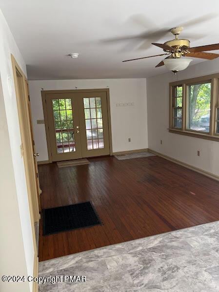 empty room featuring french doors, wood finished floors, a wealth of natural light, and baseboards