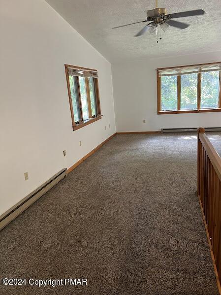 unfurnished room featuring a textured ceiling, a baseboard heating unit, carpet flooring, and lofted ceiling