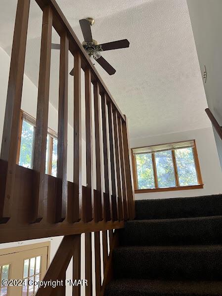 stairs featuring a textured ceiling, vaulted ceiling, and plenty of natural light