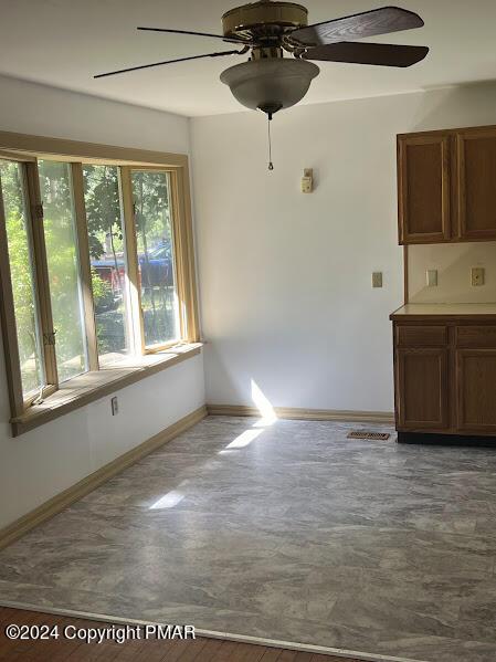 unfurnished dining area with ceiling fan and baseboards