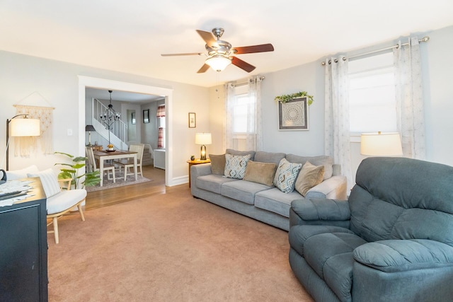 living room featuring light carpet and ceiling fan with notable chandelier