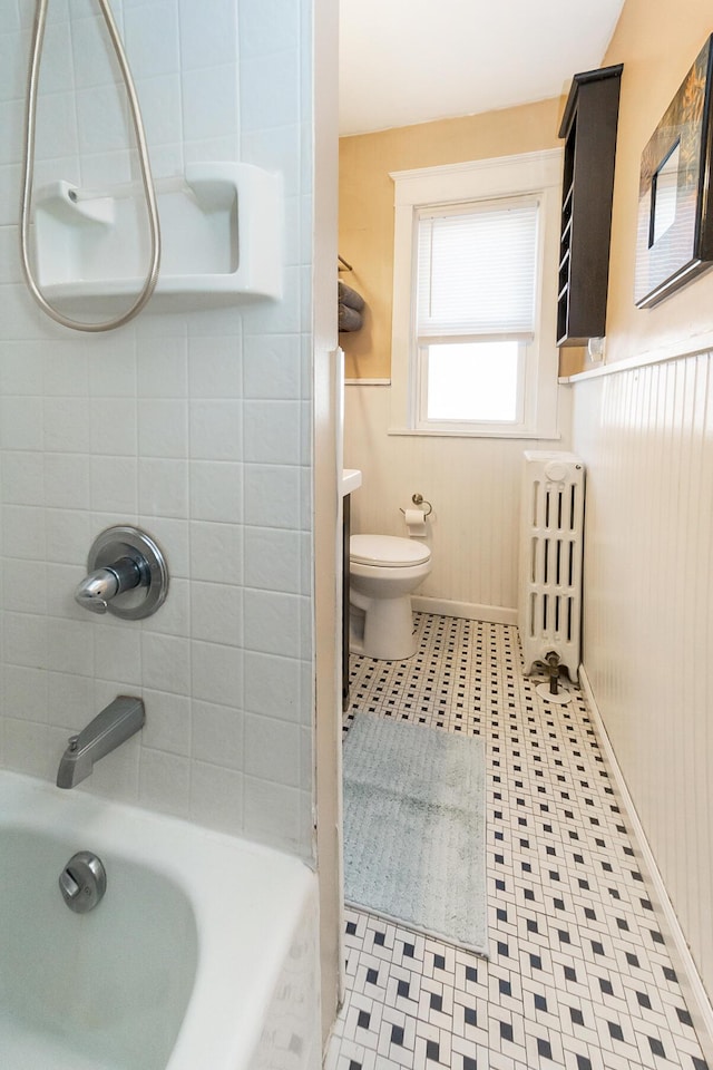 bathroom with wainscoting, toilet, radiator heating unit, and washtub / shower combination