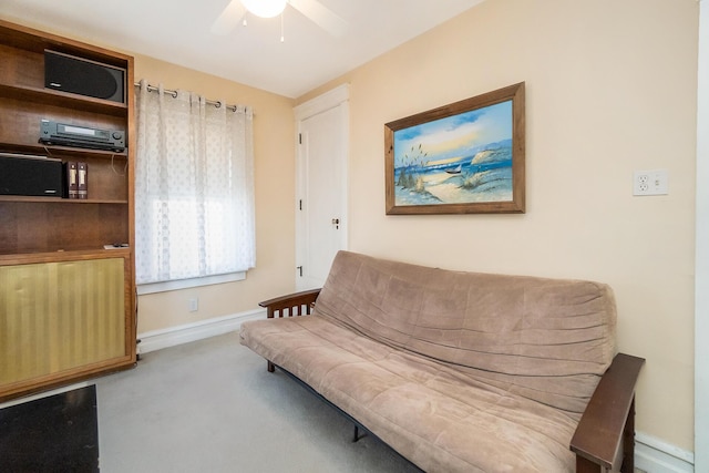 living area featuring carpet, baseboards, and ceiling fan