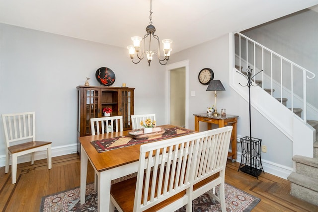 dining area featuring stairs, parquet floors, a notable chandelier, and baseboards