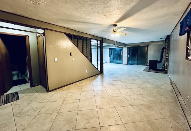 6069 Boardwalk Dr, Tobyhanna, PA 18466 - unfurnished room with a wood stove, a ceiling fan, stairs, a textured ceiling, and light tile patterned floors