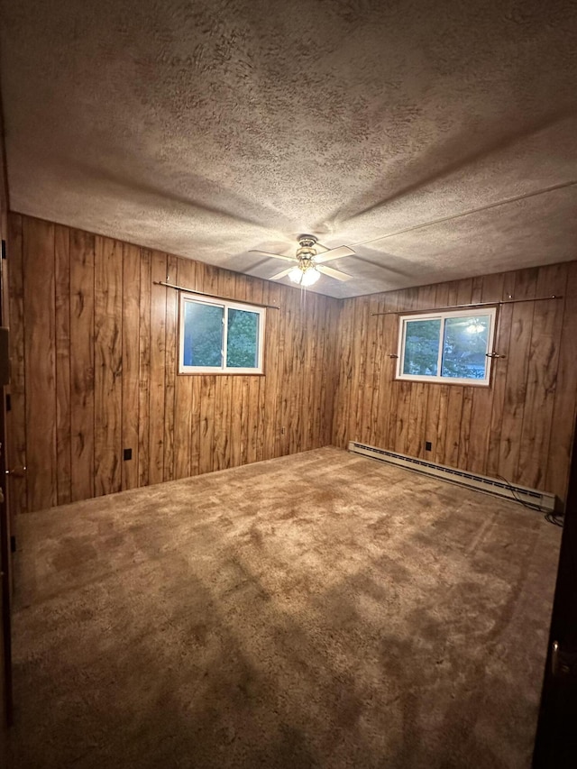6069 Boardwalk Dr, Tobyhanna, PA 18466 - spare room with wooden walls, a baseboard heating unit, carpet, a ceiling fan, and a textured ceiling