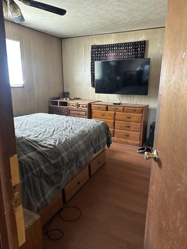 6069 Boardwalk Dr, Tobyhanna, PA 18466 - bedroom with wood finished floors, wooden walls, a textured ceiling, and ceiling fan
