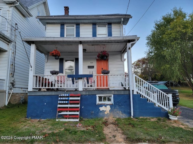 view of front of property with a porch, a chimney, and stairway