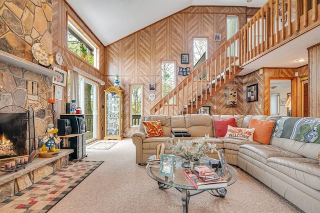 176 Manchester Dr, Bushkill, PA 18324 - living area with high vaulted ceiling, stairway, carpet, wooden walls, and a stone fireplace