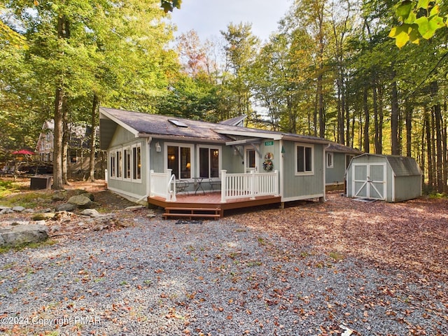 view of front of house featuring a wooden deck, a storage unit, and an outbuilding