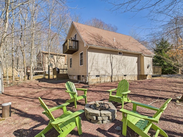 back of house with dirt driveway, an outdoor fire pit, a shingled roof, crawl space, and a balcony