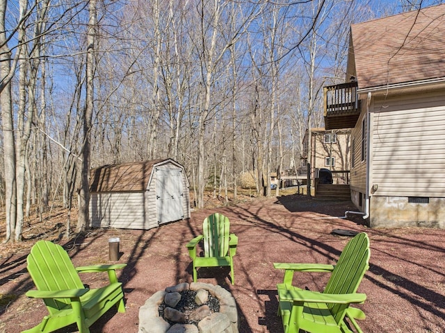 view of yard featuring a storage shed, a fire pit, and an outdoor structure