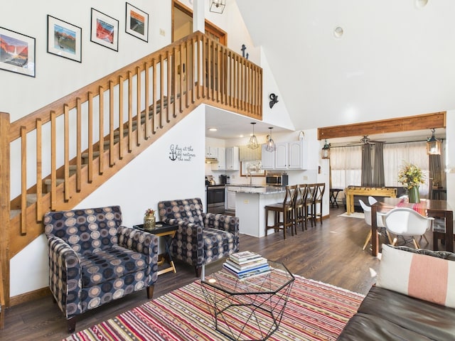 living room featuring dark wood-style flooring, recessed lighting, a high ceiling, baseboards, and stairs