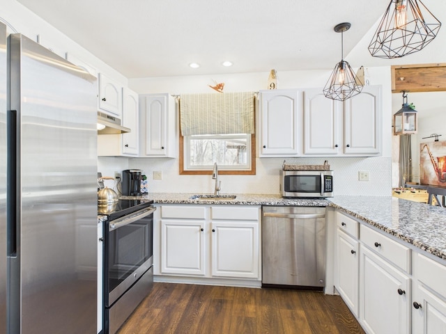 kitchen with a sink, under cabinet range hood, dark wood finished floors, white cabinetry, and appliances with stainless steel finishes