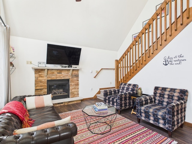 living room with baseboards, stairway, lofted ceiling, a stone fireplace, and wood finished floors