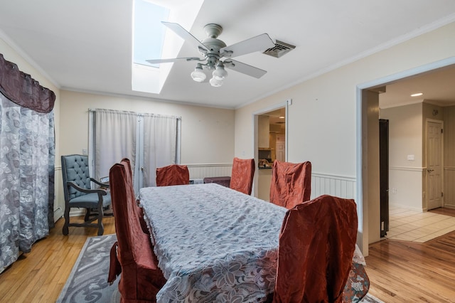 109 Little Doe Ln, East Stroudsburg, PA 18301 - dining room featuring a skylight, a ceiling fan, light wood-type flooring, wainscoting, and crown molding