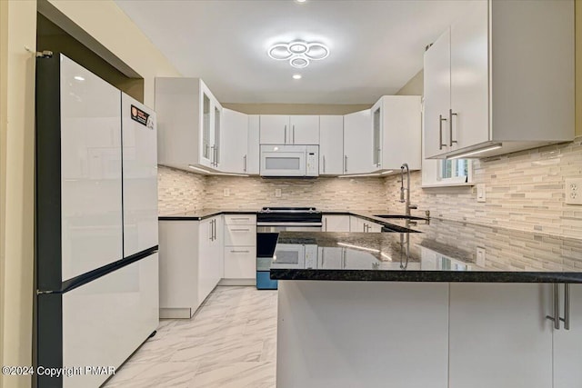 kitchen featuring white appliances, dark stone counters, a peninsula, marble finish floor, and a sink