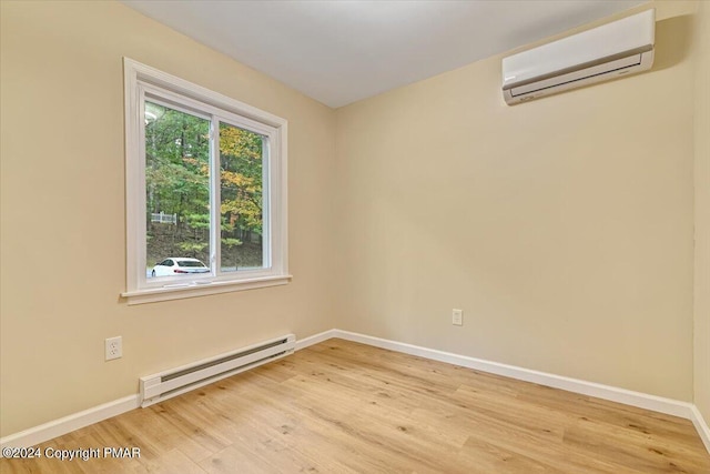 spare room featuring light wood-style floors, baseboards, a wall unit AC, and baseboard heating