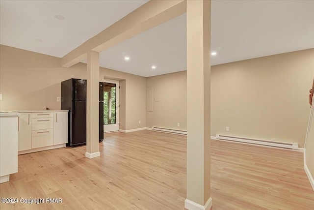 below grade area featuring light wood finished floors, baseboards, a baseboard radiator, freestanding refrigerator, and a baseboard heating unit