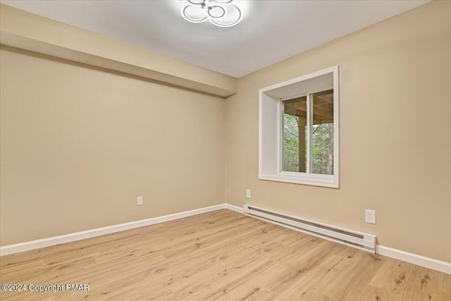 unfurnished room with a baseboard radiator, baseboards, and wood finished floors