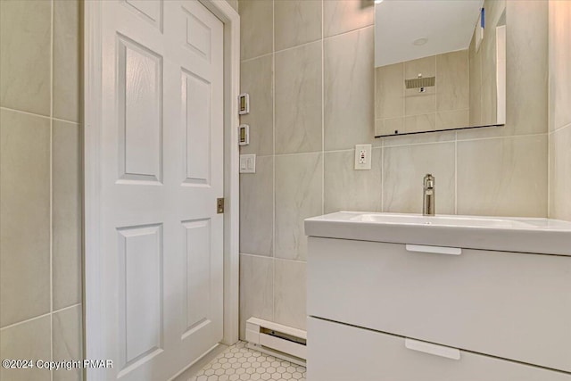 bathroom with a baseboard heating unit, tile patterned flooring, vanity, and tile walls