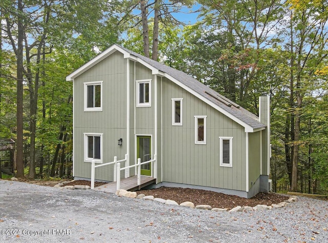 exterior space with a shingled roof and a chimney