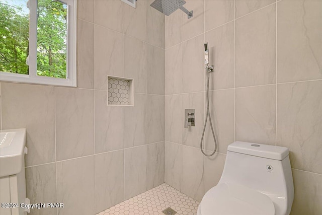 bathroom with toilet, a tile shower, and tile walls