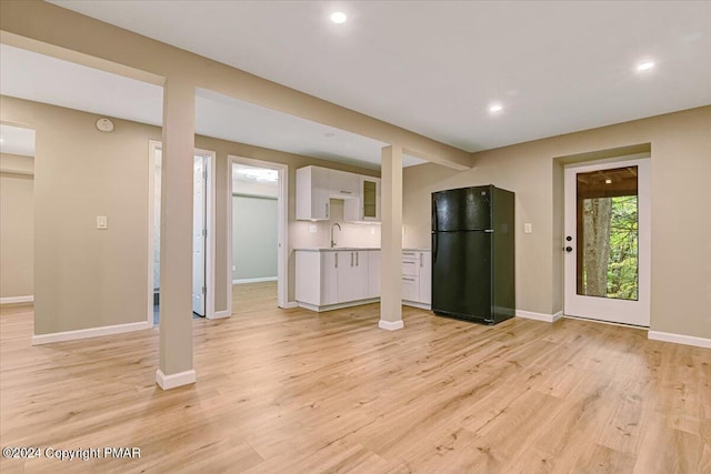 unfurnished living room featuring light wood-type flooring, a sink, baseboards, and recessed lighting