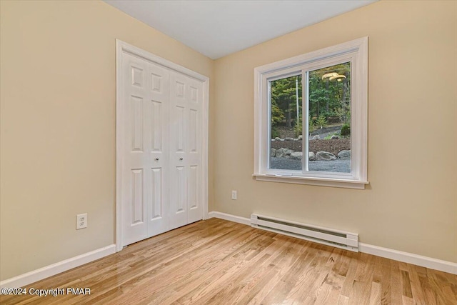 empty room with light wood-style floors, baseboards, and a baseboard heating unit